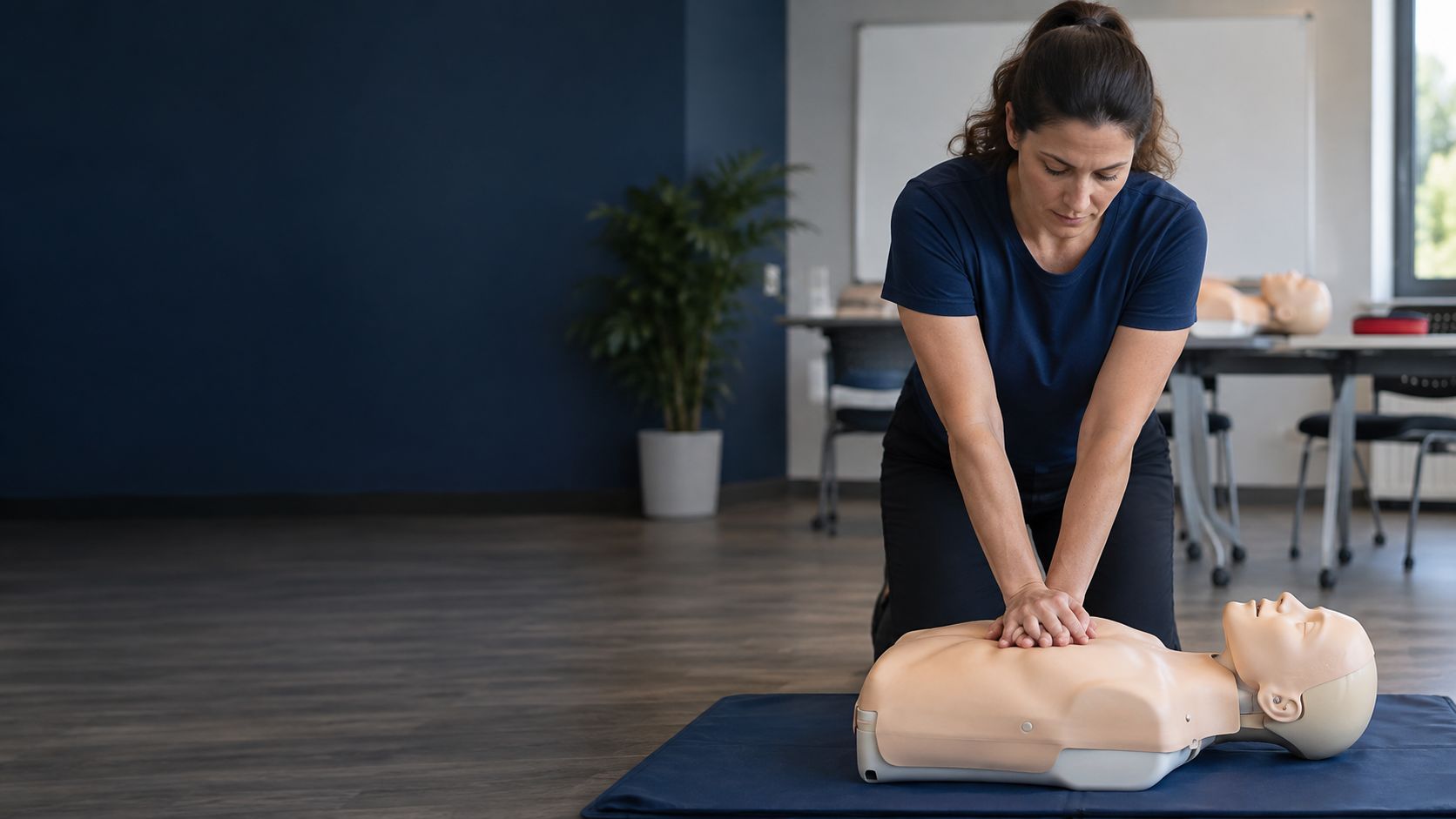 Woman performing chest compressions on a CPR training manikin during a hands-on class